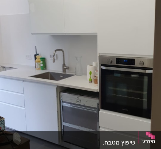 מטבח עם ארונות לבנים, כיור וברז מותקנים